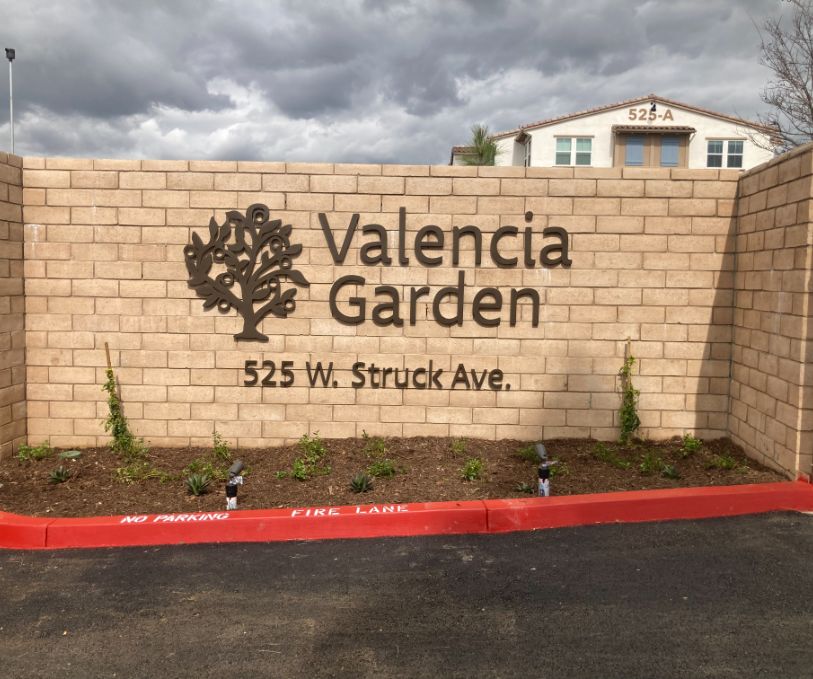 A sign that says valencia garden on the side of a brick wall.