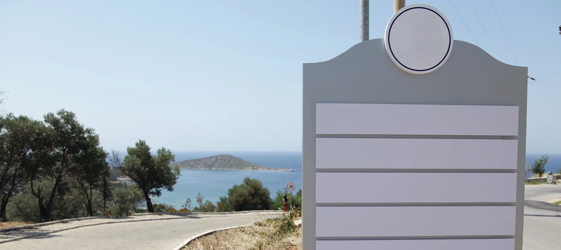 A sign on the side of a road with a view of water.